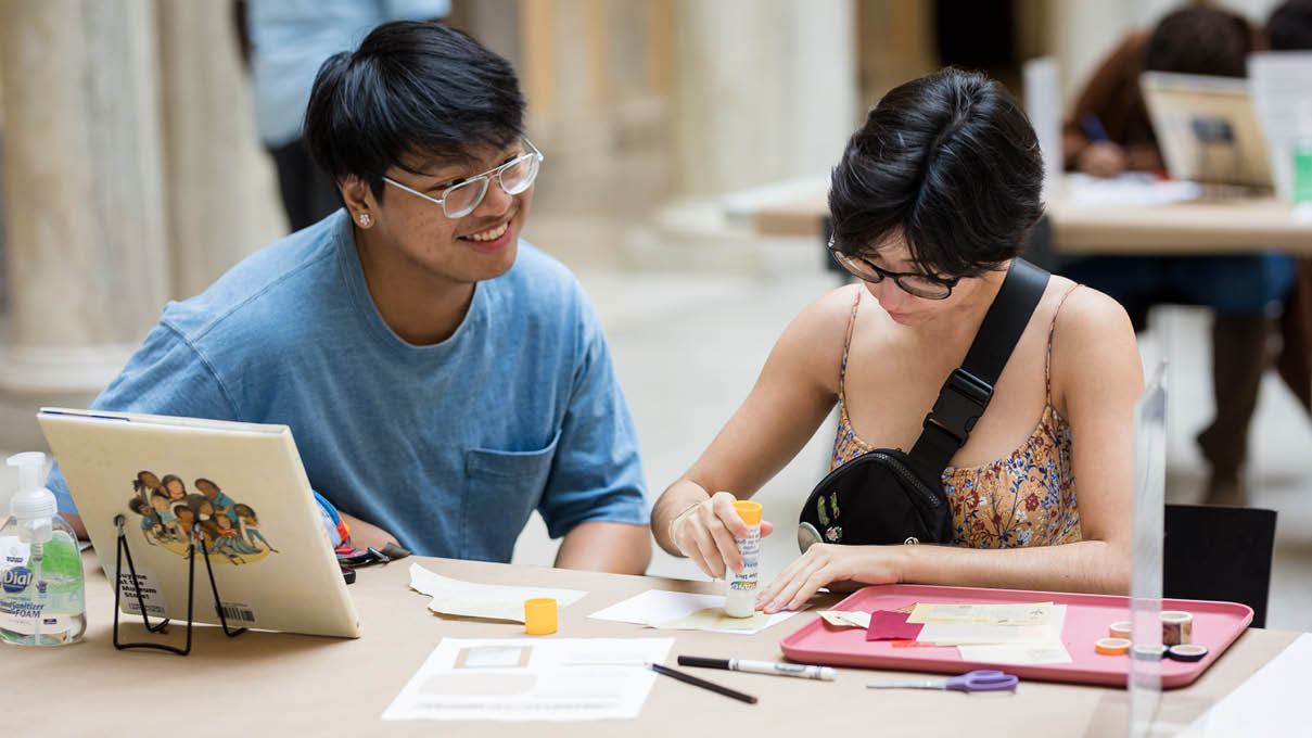 Two museum visitors seated at a table making art together